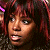 Pixelated close-up of a person with dark brown hair and light skin, mouth open in a speaking expression, against a dark background with red and purple tones.