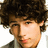 A pixelated image of a person with curly brown hair and light skin, next to blue text repeating 'nick jonas' in alternating order.