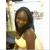A woman with long dark hair wearing a yellow sleeveless top, smiling with eyes closed in a static image with a blurred background.