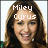 Two side-by-side pixelated images of a smiling woman with long brown hair, each with overlaid text above her head.