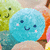A pixelated blue circular character with a smiling face and pink cheeks appears in a of colorful ice cream cone shapes, with the name 'kayla' displayed in white text on a blue background in one view