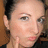 Pixelated close-up of a person's face with light skin tone, brown eyes, and dark hair, wearing a dark top against a brown background.