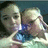 Two people in a close-up pose with one person holding a blue object, next to pixelated blue text on a black background.