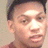 Pixelated close-up of a person's face with short dark hair, light skin, and a neutral expression against a plain light background.