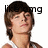 Pixelated image of a person with brown hair and light skin, wearing a white shirt, with partial text 'ing' visible on the right side.