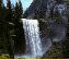 Pixelated waterfall scene with two waterfalls, dark trees, and rocky mountains under a light blue sky.
