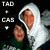 Two people pose together in a dark setting, one wearing a white hooded garment with visible wings. The image shows slight pixelation and motion blur across frames.