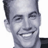 Pixelated grayscale portrait of a smiling man with short dark hair, cropped to show head and shoulders against white background.