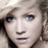 Pixelated close-up of a person's face with light brown hair, blue eyes, and a neutral expression, cropped to show only the upper face and shoulders.