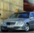 Static image of a silver sedan with dark blue roof parked near a building with beige and brown walls.