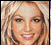 Pixelated static image of a smiling person with light brown hair and visible facial features including eyes, nose, mouth, and cheeks.