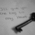 Black-and-white key-shaped icon with blurred text background, showing motion blur in the lower-left corner across frames.
