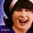 Pixelated image of a smiling person with dark hair and purple clothing, surrounded by cyan text labels on black background.