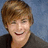 A pixelated image shows a person with short brown hair and a dark top against a blue background, next to pink text reading "he's all mine bizonches" on a dark blue background.