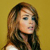 A pixelated portrait of a person with long brown hair against a solid yellow background, wearing a white sleeveless top.