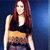 A pixelated figure with long red hair wears a black sleeveless top and yellow waistband against a blue gradient background.