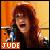 A pixelated static image shows a person with long brown hair holding a small object against a warm-toned gradient background with the text 'JUDE' at the bottom.