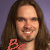 Pixelated static image of a person with long brown hair and glasses, featuring red heart-shaped text in the lower-left corner against a purple background.