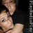 Two people in close physical proximity with one person leaning toward the other against a dark background.