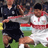 Static 48x48 pixel icon depicting two soccer players in mid-action on a field, one in dark uniform and the other in white with red accents.