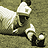 Pixelated image of a baseball player in dark uniform with white accents, holding bat and standing on field.