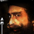 Pixelated static image of a character's face with orange-brown tones and dark background, featuring visible pixelation artifacts and partial facial features.