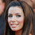 A pixelated close-up of a person with long brown hair, light skin, and a slight smile, set against a blurred background.