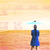 A pixelated figure in a blue dress stands facing away, holding a light blue umbrella against a gradient background with faint repeating patterns.