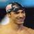 A pixelated image of a swimmer wearing a dark cap with pink accents, smiling against a blue and black background.