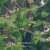 A pixelated green and brown landscape with indistinct shapes resembling trees or foliage, rendered in low resolution.