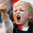 Pixelated image of a person with light hair wearing a dark suit, white shirt, and red tie, mouth open in a shout or yell.