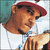 A person wearing a red and white cap and white shirt with blue accents, holding a hand near their face in a contemplative pose.