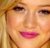 Pixelated close-up of a person's face with light brown hair, dark eyes, and pink lips against a warm-toned background.