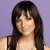 Pixelated image of a person with long dark hair and bangs, wearing a light-colored sleeveless top against a solid purple background.