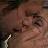Pixelated close-up of a person's face with visible eyes, nose, and mouth against a blurred background.
