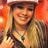 Pixelated image of a smiling person with long light brown hair wearing dark clothing and a pink headband, next to text reading #1 fan!! on white background.