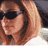 Pixelated static image of a person with long light brown hair wearing dark sunglasses, partially cropped on the left and right edges.