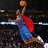 Pixelated image of a basketball player in mid-air shooting a ball, wearing a blue jersey with red accents and brown shorts.