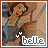 Pixelated cartoon of a woman with brown hair in blue dress leaning against wooden structure, text 'belle' below with star-like symbols.