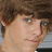 A pixelated image of a person with brown hair on the left, next to vertical pink text symbols and words on a blue background.