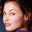 Static 48x48 pixel icon showing a close-up of a person's face with curly hair, visible ear, and blue clothing against dark background.