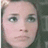 Pixelated close-up of a person's face with light skin, dark eyes, and neutral expression against a muted background.