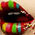 A pixelated close-up of a dark red object with colorful striped patterns on its upper and lower edges against a light beige background.