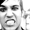 Black-and-white close-up of a person's face showing teeth, with visible hair and ear, against a blurred background.