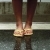 A pixelated close-up of two feet in light-colored shoes standing on a reflective surface with a blurred background.