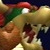 Pixelated image of a character with brown skin, green cap, red nose, and white eyes, holding a yellow object against a dark background.
