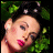 Two side-by-side pixelated images of a woman with dark hair, one showing her lying on green foliage and the other facing forward with white flowers in her hair.