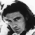 Black-and-white pixelated static image of a person's face with dark hair and formal attire, likely from an early digital avatar or celebrity icon.