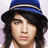 Pixelated portrait of a person with long dark hair wearing a blue hat and white shirt against light purple background.
