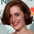 A pixelated close-up of a person with brown hair, red lips, and a light-colored background with partial text elements.